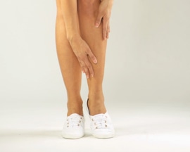 Femeie masându-și gambele obosite cu Lioton 1000 Gel, fără a lăsa urme