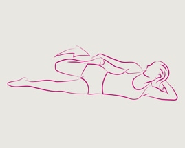 Женщина лежит на боку и тянется к верхней ноге, чтобы выполнить растяжение четырехглавой мышцы.